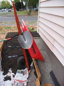 Wheelbarrow dumping pea gravel into planting bed