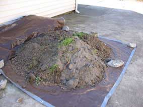 Clearing top layer of weeds, clay, gravel, and plastic