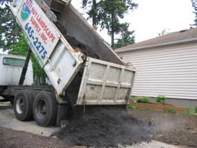 Dumptruck dropping load of topsoil for lawn