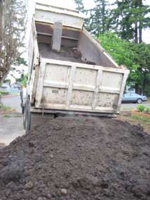 Dumptruck dropping load of topsoil for lawn