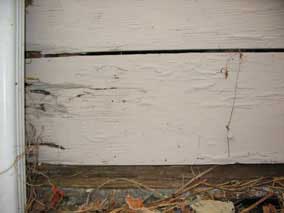 Garage sill plate exposed to outside, near ground level, with wood siding above