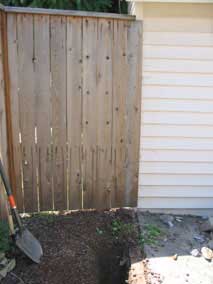 Fence next to garage with electrical trench approaching