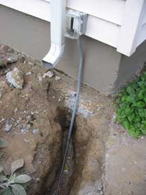 New GFCI exterior outlet at back corner of house, with line to garage going down into trench