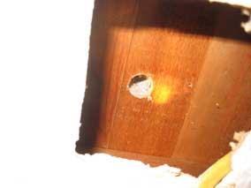 Hole drilled through floor above to run electrical wire up inside wall.