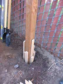 Shimming new post with wood stakes