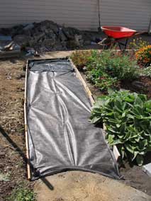 Landscaping fabric over tamped base for new pavers