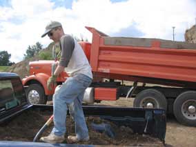 Shoveling dirt out of the pickup the hard way while dump truck does it the easy way